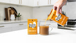 Kettle & Fire mushroom chicken bone broth carton being poured into a glass mug in a kitchen setting.