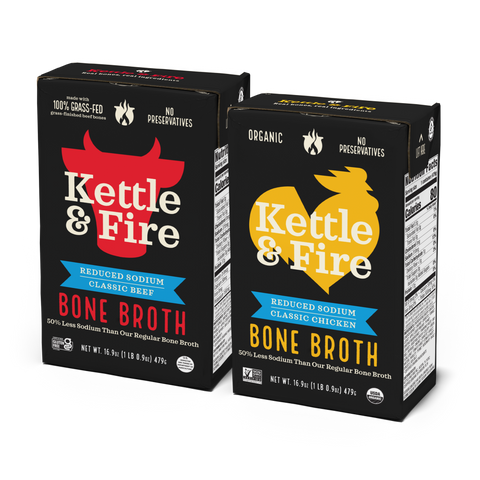 Two Kettle & Fire bone broth cartons: beef with red bull logo on black box, chicken with yellow rooster logo on black box.