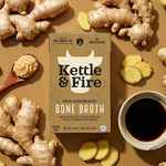 Kettle & Fire miso ginger beef bone broth package surrounded by fresh ginger root, ginger slices, and dark broth in a bowl.
